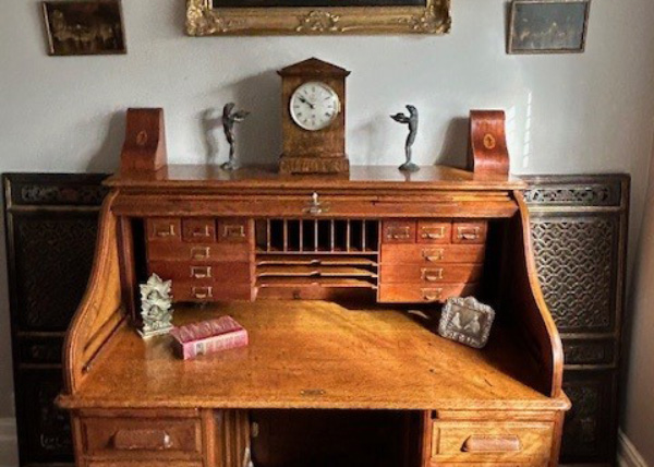 a vintage wooden desk with a clock decorative items and several drawers showcasing timeless craftsmanship and design elements from the 1900s featuring seven functional compartments