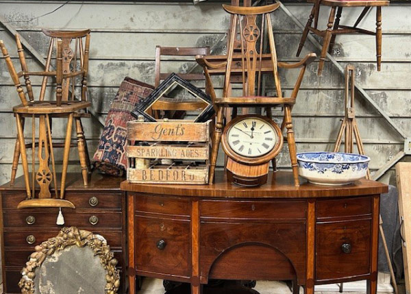 vintage furniture display with antique chairs, wooden clock, decorative items and a rustic crate showcasing historical craftsmanship and charm