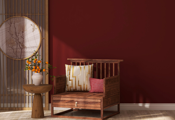 wooden chair with colorful cushions next to a round table holding a white vase with orange flowers against a red wall modern interior design five elements of decor